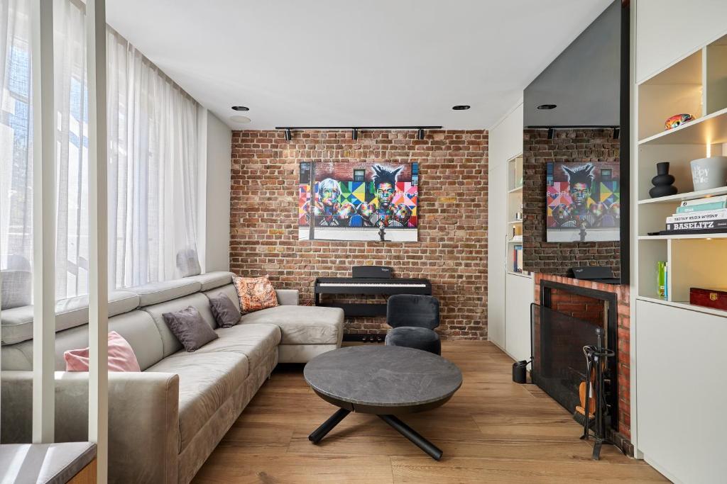 un salon avec un canapé et un mur de briques dans l'établissement Morny Haven - A 500m de la plage, à Deauville
