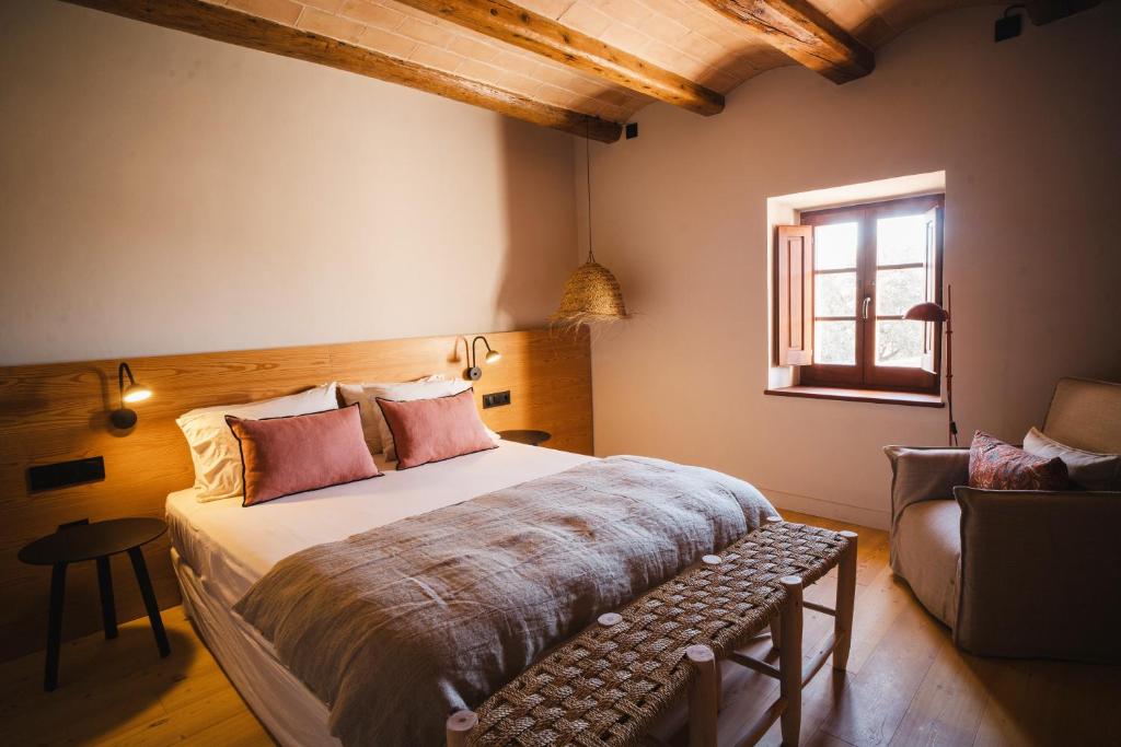 a bedroom with a bed and a chair and a window at Hotel-Masia Can Farrés in El Bruc