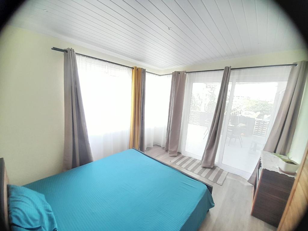 a bedroom with a blue bed and large windows at Rooftop apartment in Port Louis