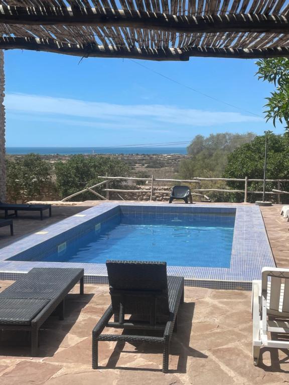 uma piscina com uma mesa e duas cadeiras e uma mesa em Chill House surf camp em Sidi Kaouki