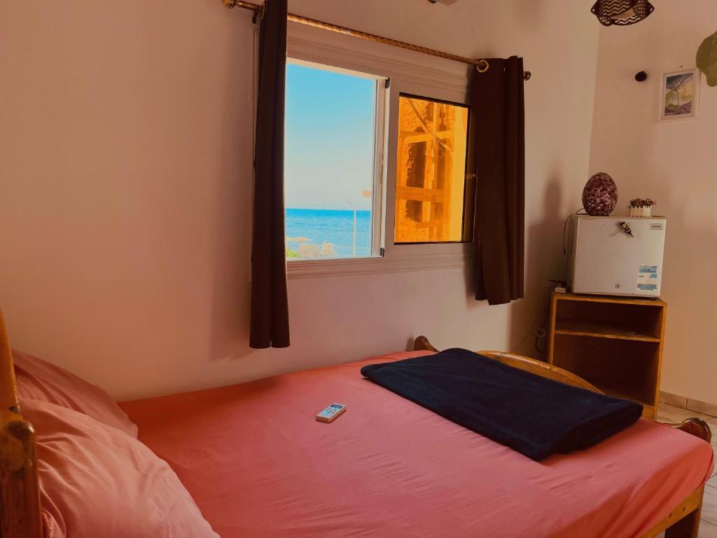 a bedroom with a bed and a window with the ocean at Nook in Dahab