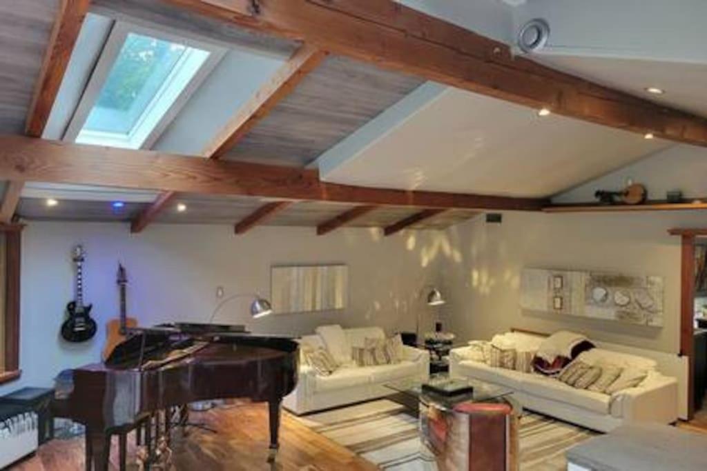 sala de estar con sofá y piano en Anthropocene Jewel Cottage en Milton