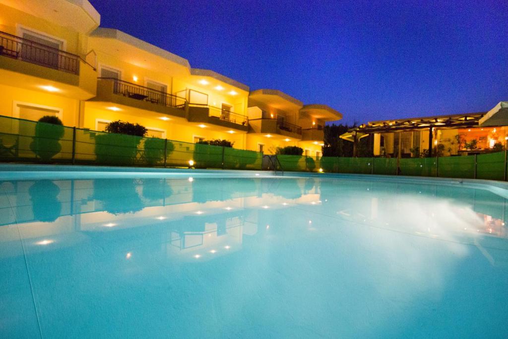 a swimming pool in front of a building at night at Vakis apartments in Zakharo