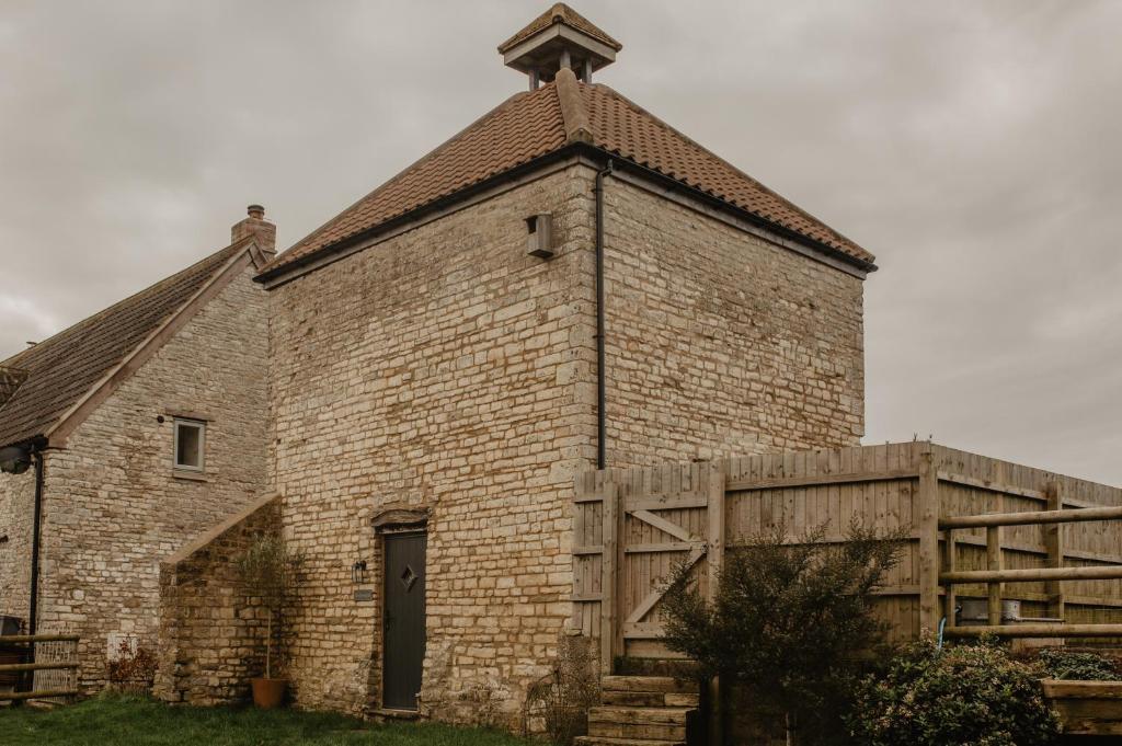 ein altes Backsteingebäude mit einem Kreuz darüber in der Unterkunft The Dovecote - Collins Farm in Bristol