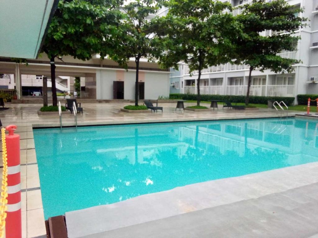 a large swimming pool with blue water in a building at Fairview Trees Residences Staycation in Manila