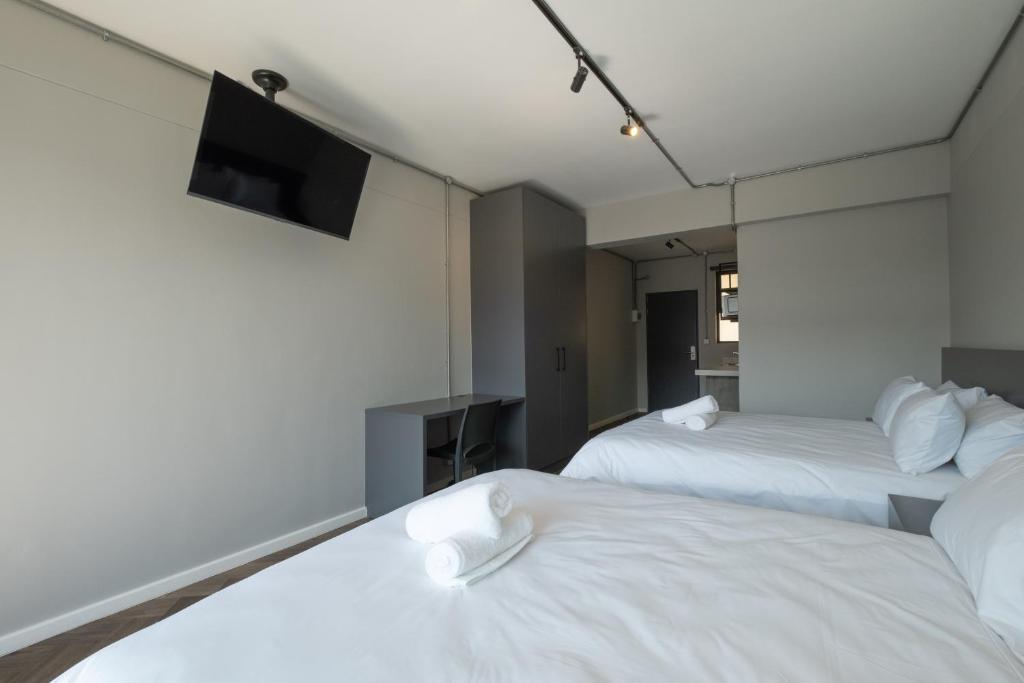 Habitación de hotel con 2 camas y TV de pantalla plana. en Inn & Out Plus Rosebank en Johannesburgo