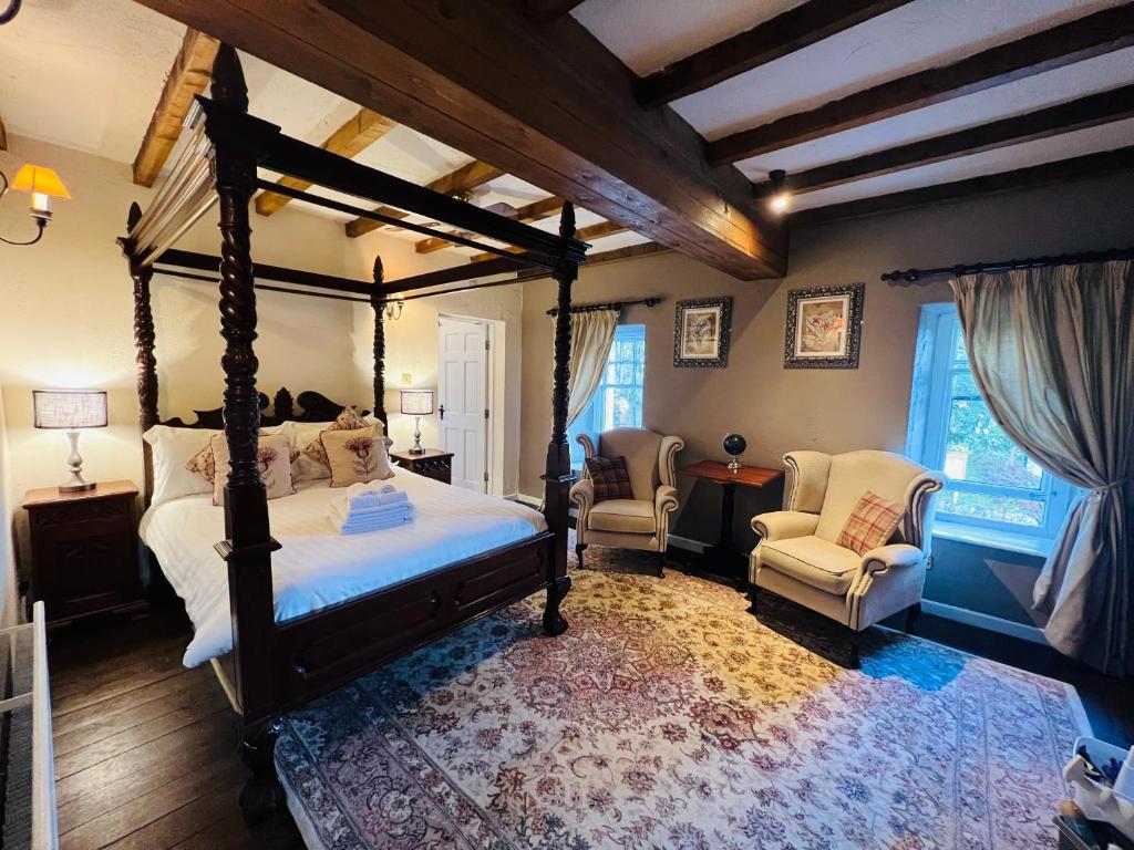 a bedroom with a canopy bed and two chairs at Peak Hotel Castleton in Castleton