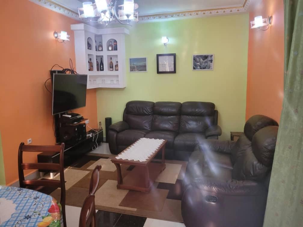 a living room with a leather couch and a tv at Olympus House in Yaoundé