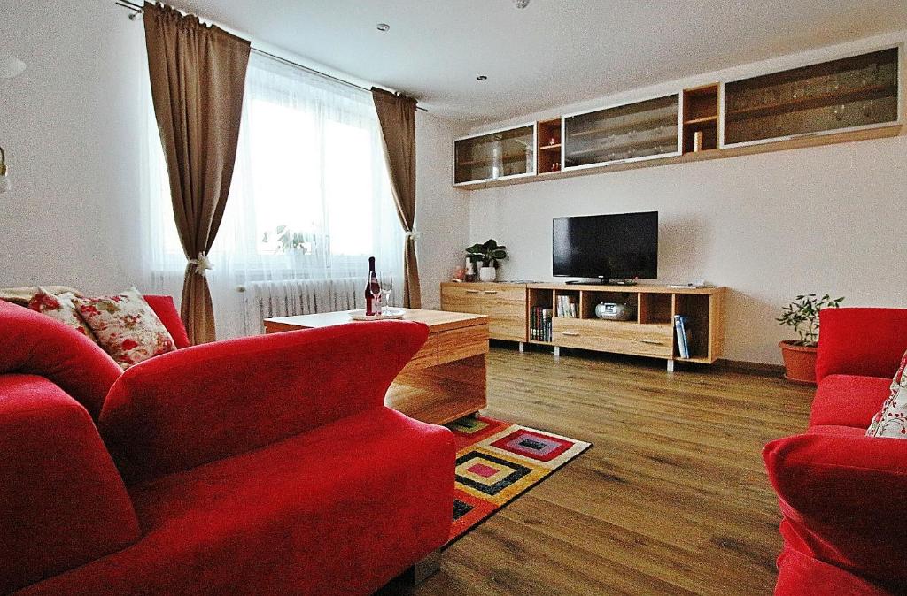 sala de estar con sofá rojo y TV de pantalla plana en Apartmán 4M Tatry, en Tatranská Štrba
