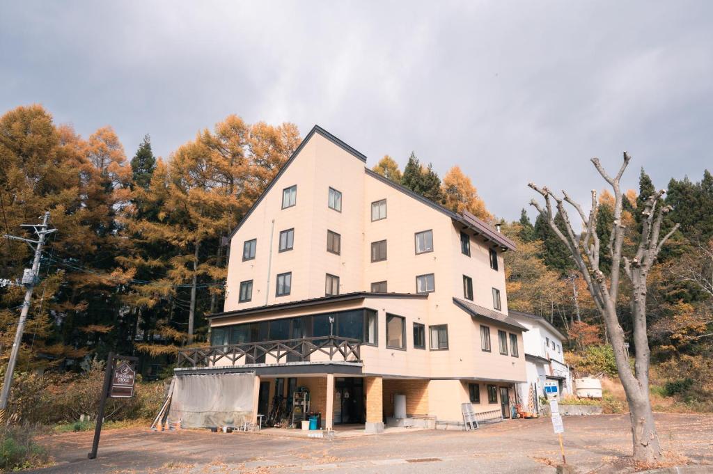 a large white building with trees in the background at 豊島ロッヂooバス停浅貝上前 in Yuzawa