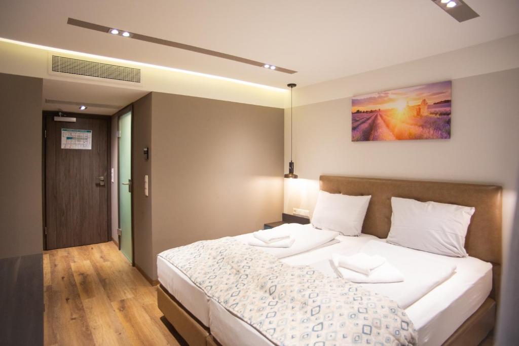 1 dormitorio con 1 cama grande con sábanas blancas en ASD Hotel en Filderstadt