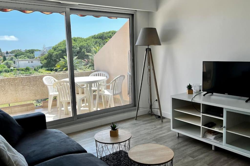 un salon avec un canapé, une télévision et une table dans l'établissement Appartement avec piscine et terrain de tennis, à Antibes