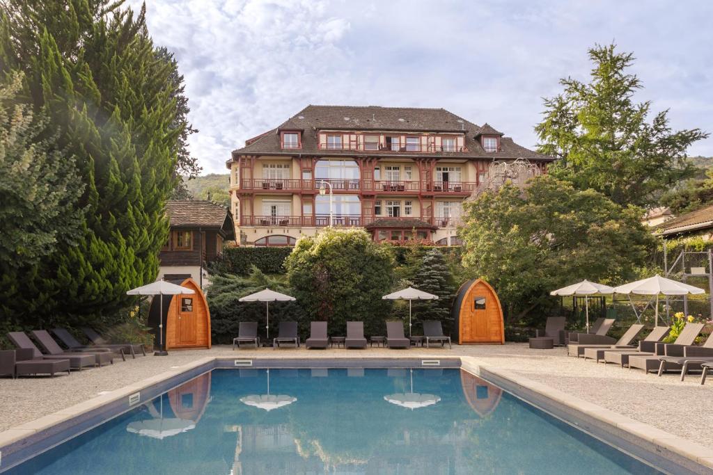 un hôtel avec une piscine en face d'un bâtiment dans l'établissement La Verniaz et ses Chalets, à Évian-les-Bains
