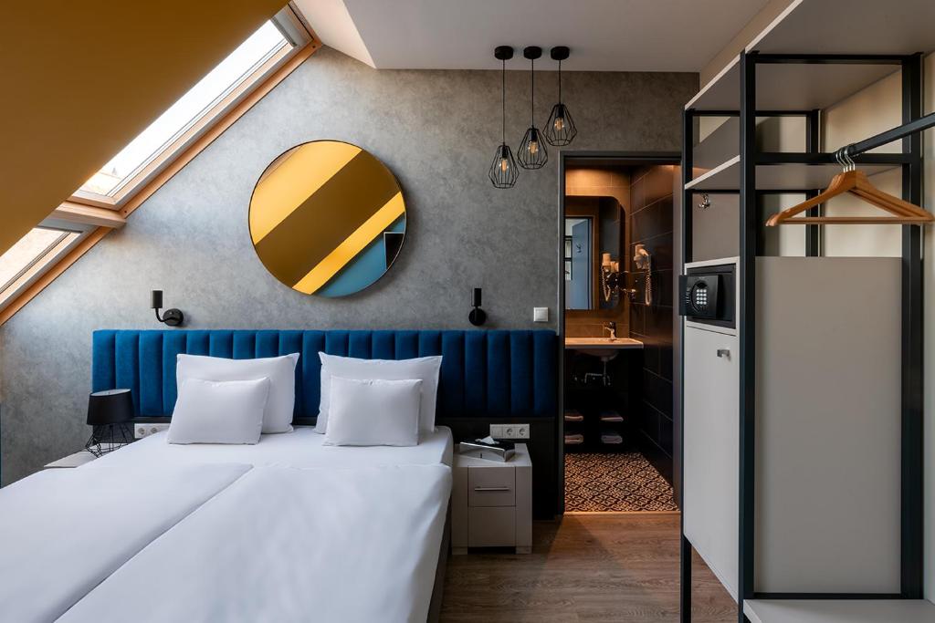 1 dormitorio con 1 cama con cabecero azul y espejo en Alta Moda Fashion Hotel, en Budapest