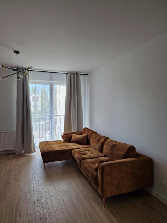 un sofá marrón en una sala de estar con una gran ventana en Apartament Staromiejski Rapackiego 45 en Grudziądz