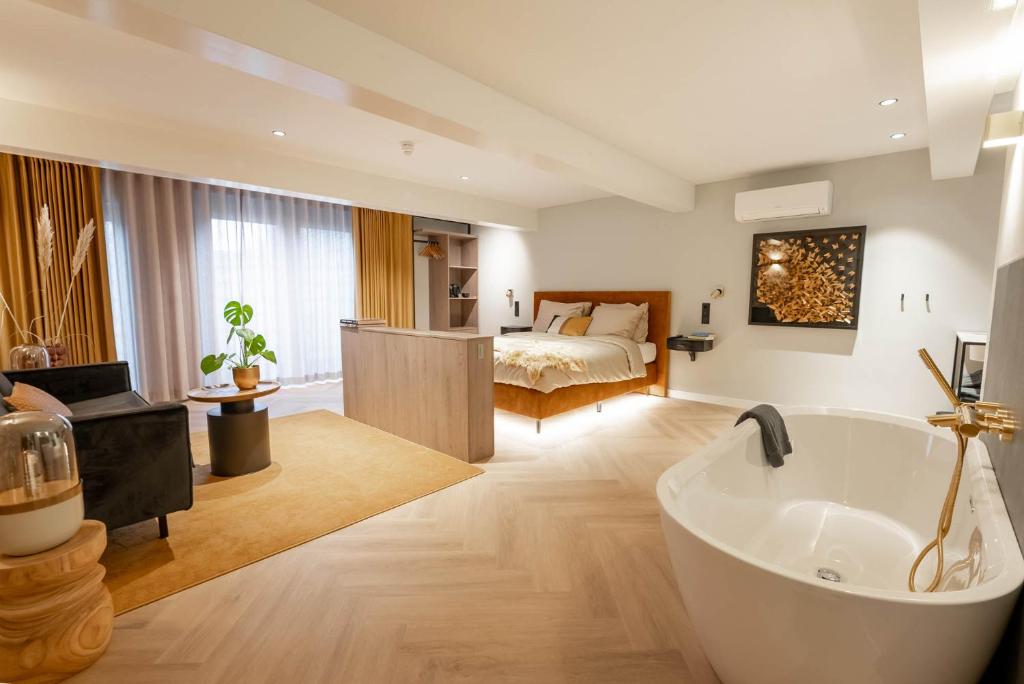 een badkamer met een bad en een slaapkamer met een bed bij Boetiekhotel Faan - NIEUW! in Ballum