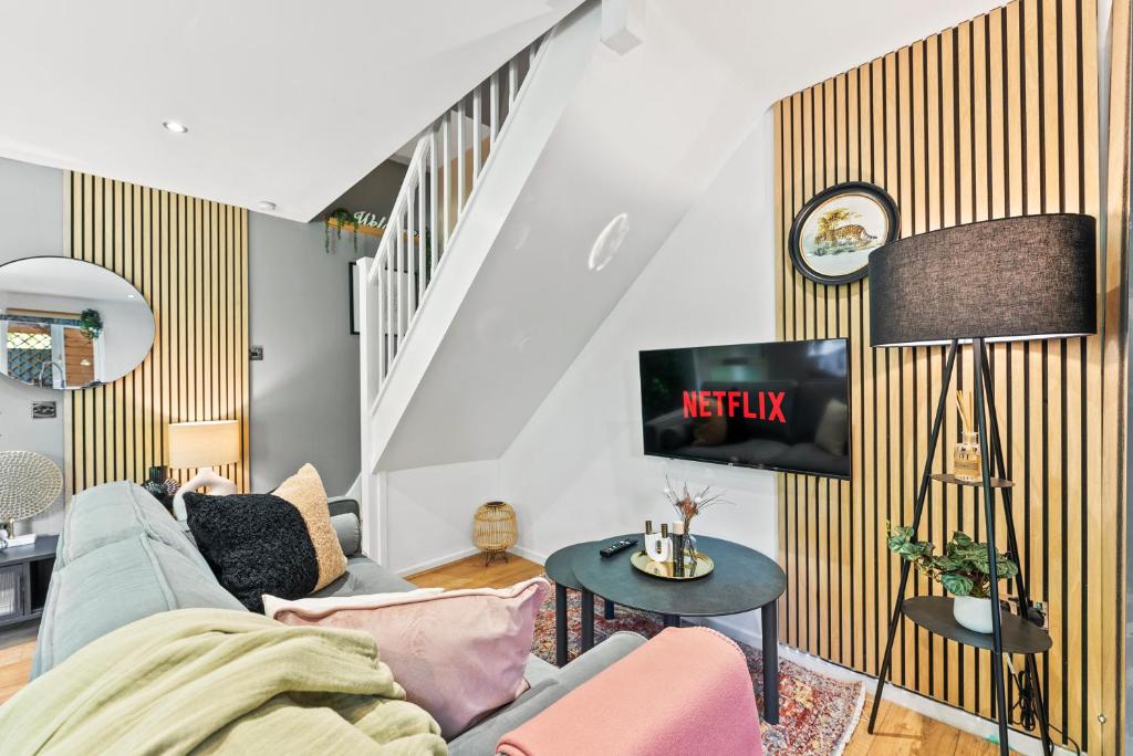 ein Wohnzimmer mit einem Sofa und einem TV an der Wand in der Unterkunft Beautiful House in Cambridge - Sleeps 6 in Milton
