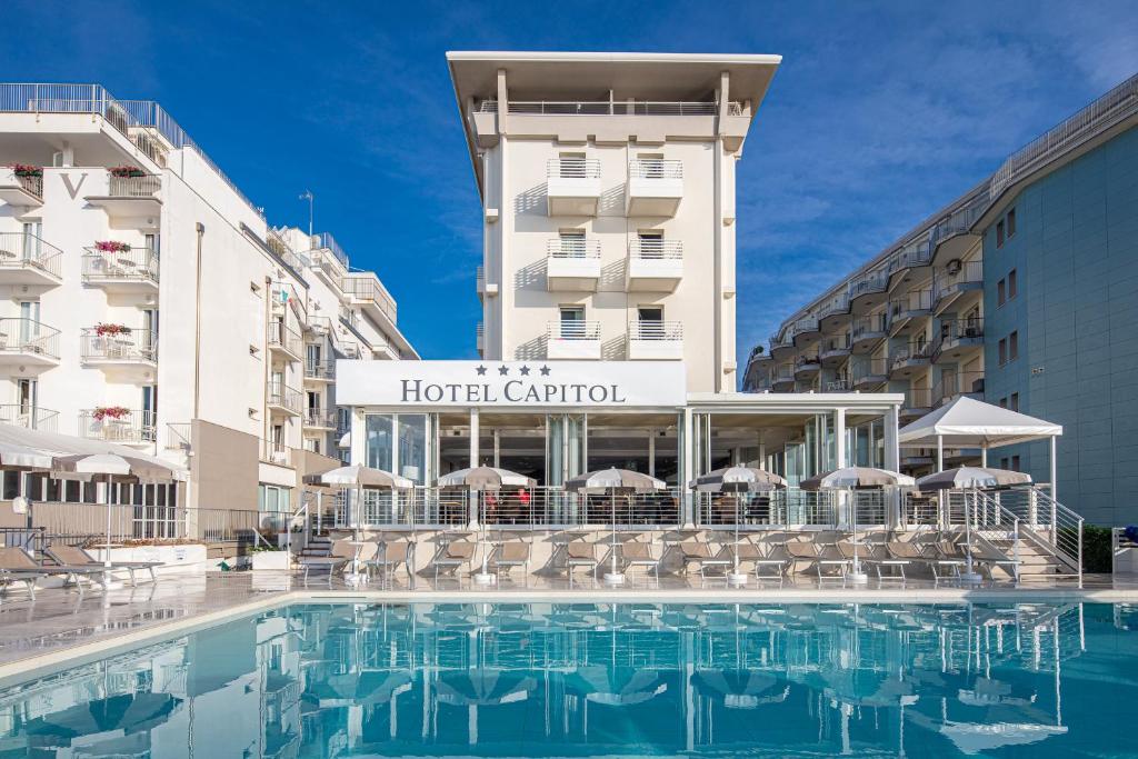 um hotel com piscina em frente a um centro hoteleiro em Hotel Capitol em Lido di Jesolo