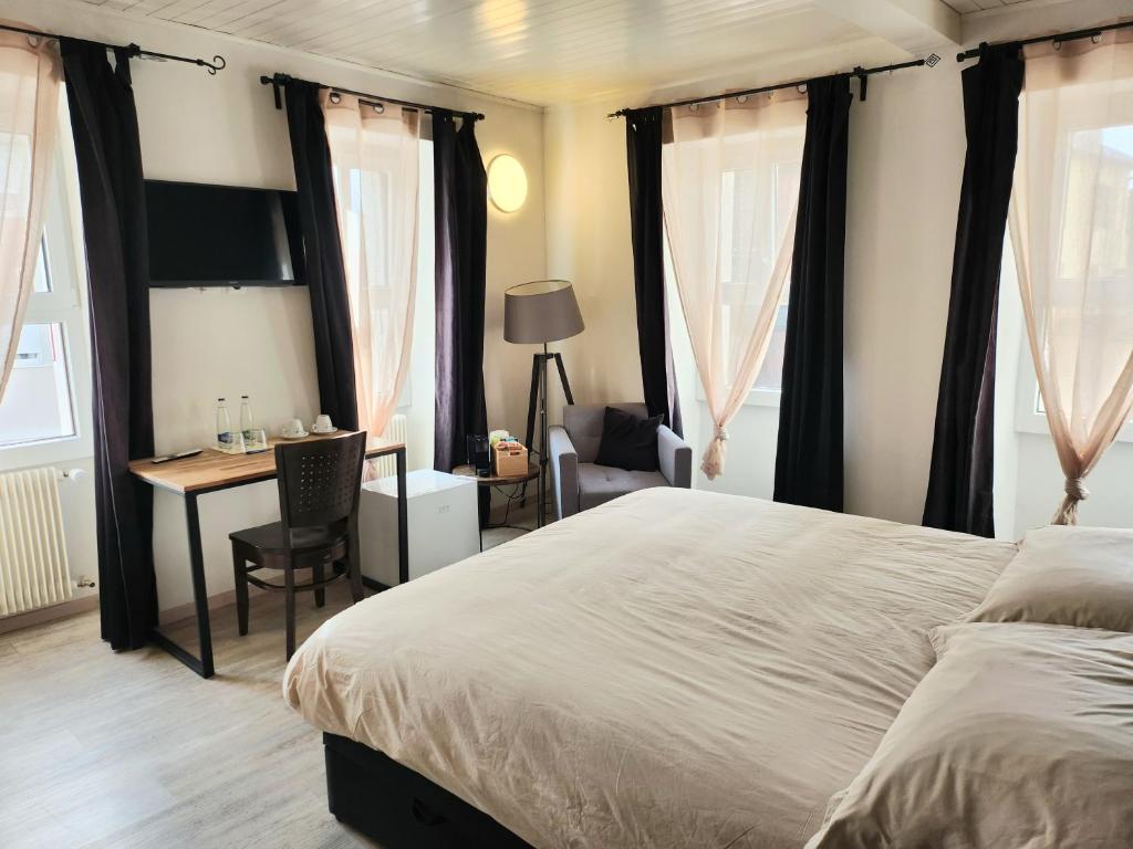 een slaapkamer met een groot bed, een bureau en een tafel bij Auberge de l’Union in Lens