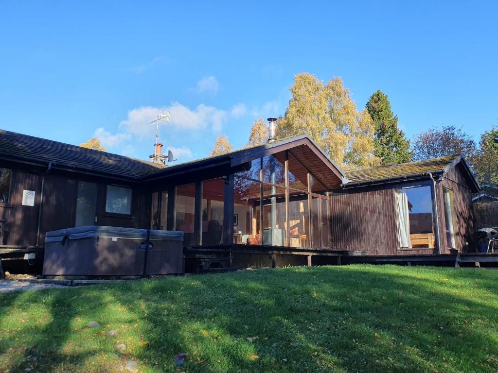 a house with large windows and a green lawn at Ptarmigan Lodge Nethy Bridge in Nethy Bridge