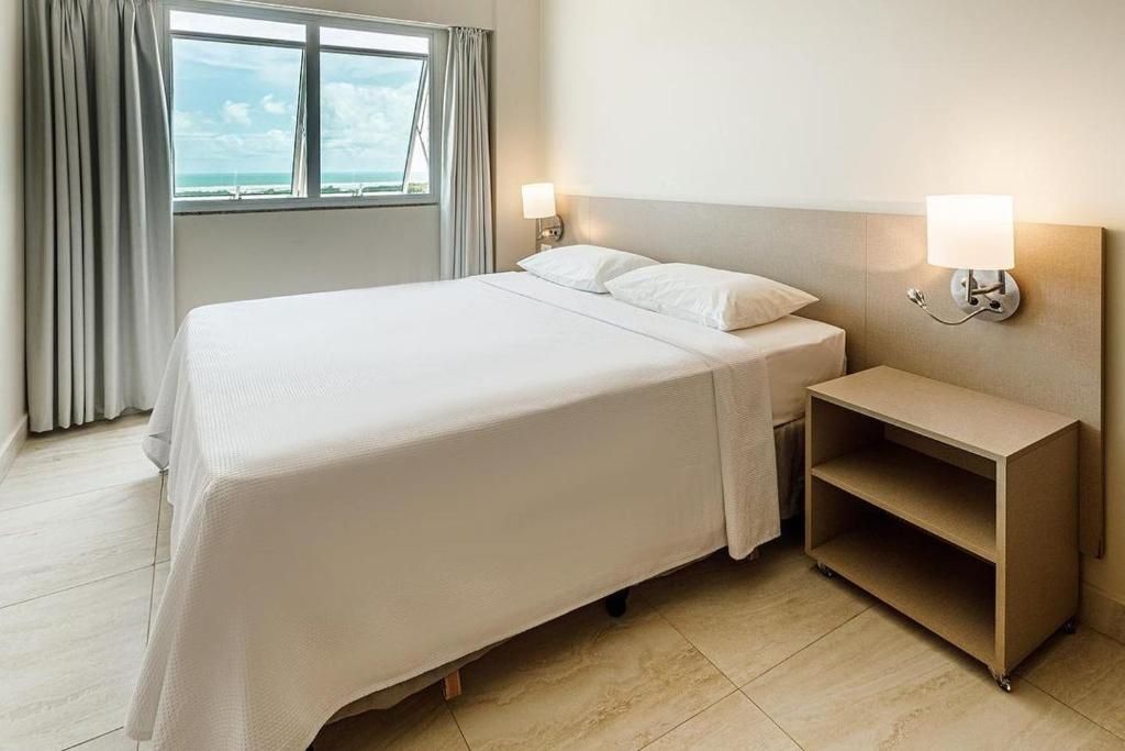 Un dormitorio con una gran cama blanca y una ventana en Salinas Park Resort, en Salinópolis