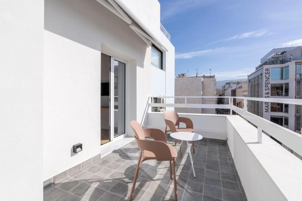 un balcon avec des chaises et une table sur un immeuble dans l'établissement ERMOU 40 SUITES, à Athènes