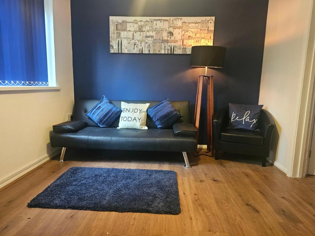 a living room with a black couch and a chair at Hereford House - Welcome Short Stays in Derby