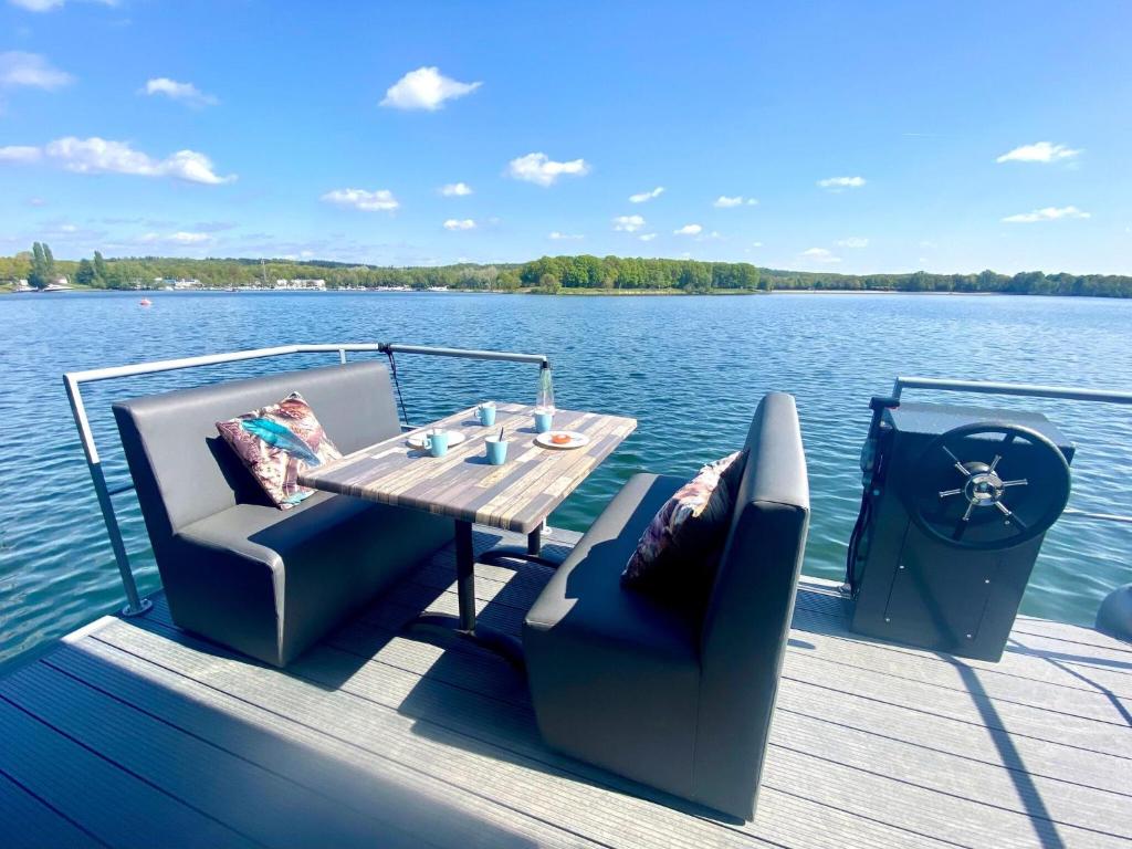 a wooden dock with a table and chairs on the water at Luxury houseboat with beautiful views over the Mookerplas in Middelaar