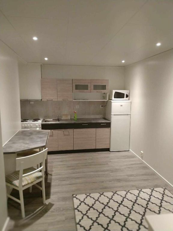 a large kitchen with a table and a microwave at apartament by the sea in Havøysund