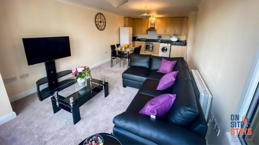 a living room with a black leather couch and purple pillows at OnSiteStays - 2 Bedroom Apartment with Ensuite, Free Parking & Wi-Fi in Gravesend