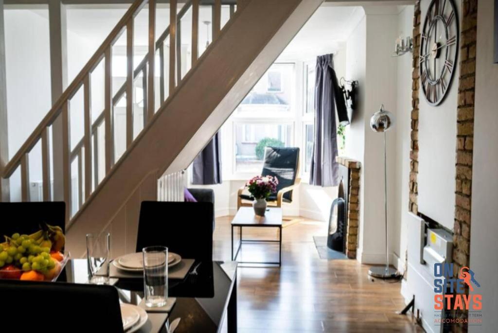 ein Wohnzimmer mit einem Esstisch und einer Treppe in der Unterkunft OnSiteStays - Contractor Friendly Retreat, 2-BR Terrace House near A2 in Gravesend