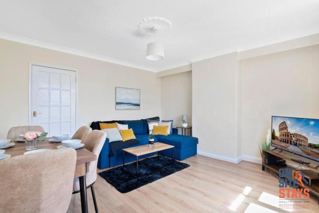 a living room with a blue couch and a tv at OnSiteStays - Comfortable Contractor Accommodation, 3-BR House, WIFI, Parking & Large Garden in Enfield Lock