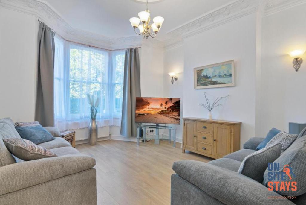 uma sala de estar com dois sofás e uma televisão em OnSiteStays - Tranquil 2 Bedroom Apartment with Large Kitchen, Private Garden near Wimbledon Station em Londres