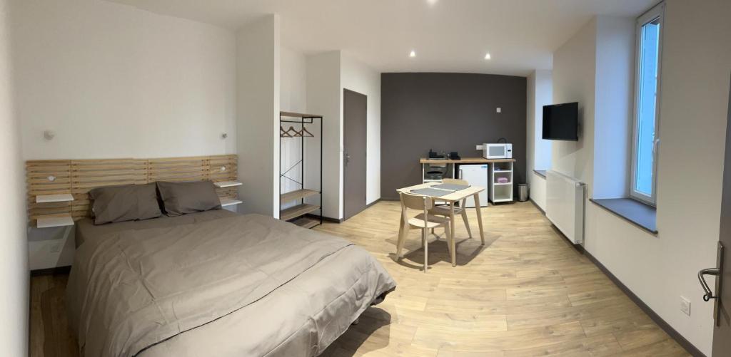 ein Schlafzimmer mit Bett und Tisch und eine Küche in der Unterkunft La Cigogne in Panissières