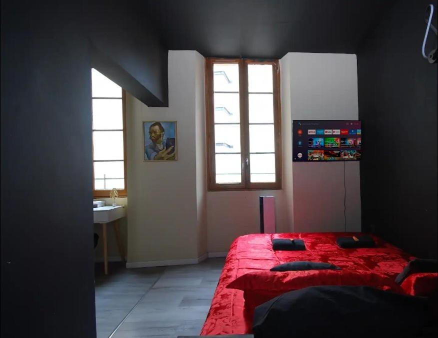 1 dormitorio con cama roja y ventana en Baignoire Cosy Centre Narbonne en Narbona