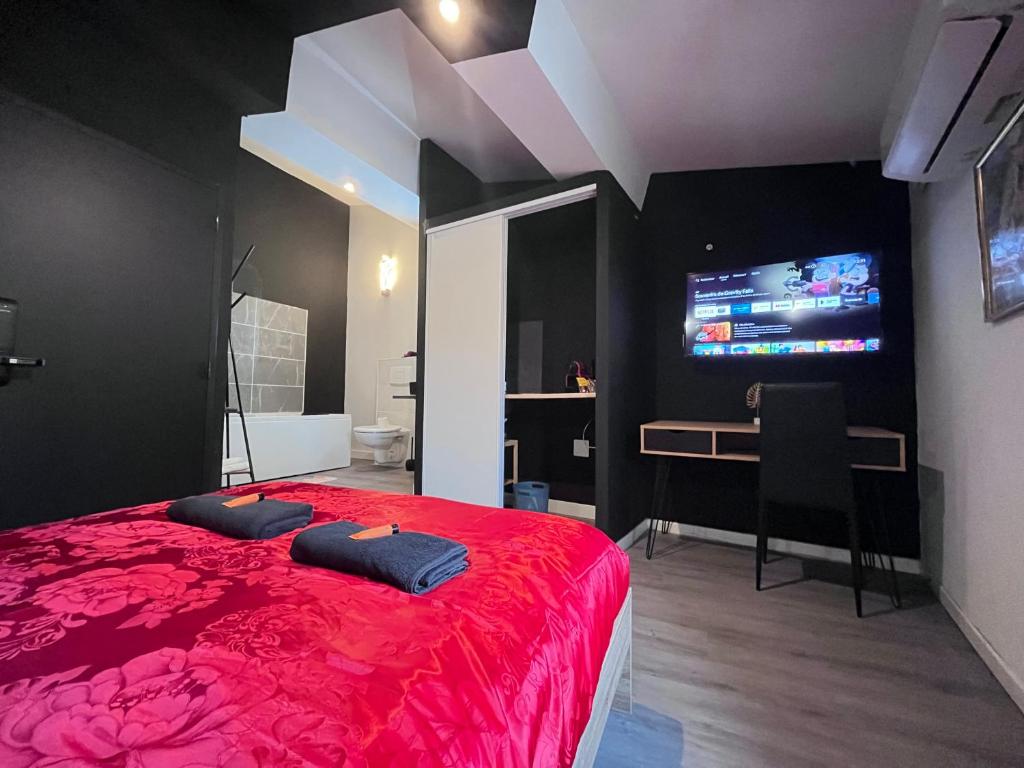 1 dormitorio con cama roja, escritorio y TV en Studio Baignoire centre ville en Narbona