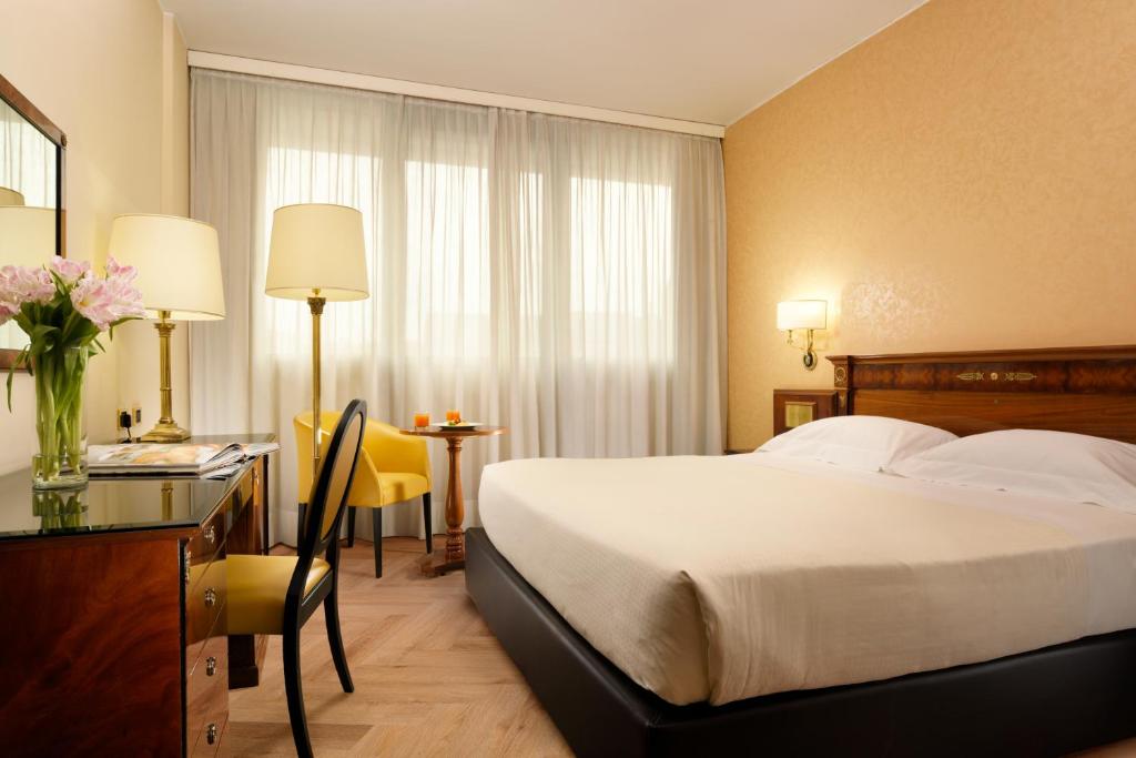 ミラノにあるUNAHOTELS Scandinavia Milanoのベッドとデスクが備わるホテルルームと