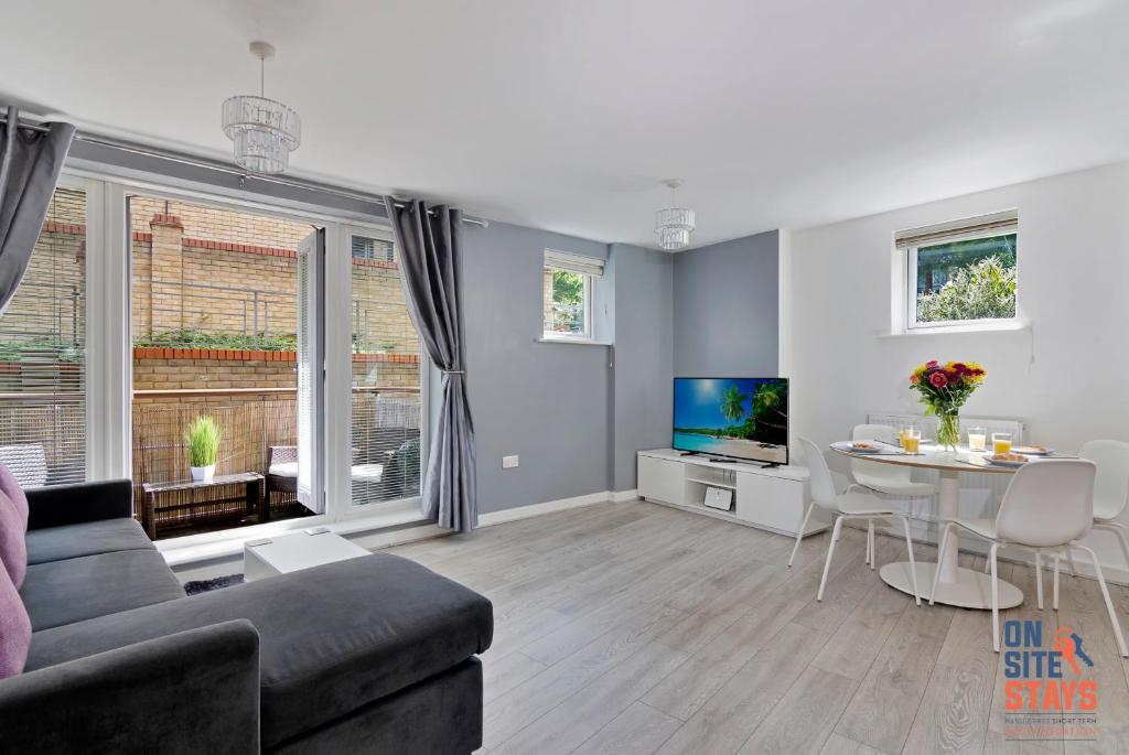 ein Wohnzimmer mit einem Sofa, einem TV und einem Tisch in der Unterkunft OnSiteStays - Contemporary 2 Bed Apt with Ensuite, 2 x Free Parking Spaces & a Balcony in Dartford