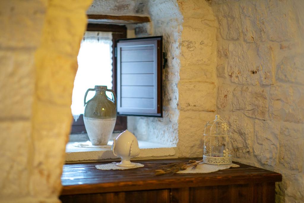 Zimmer mit einem Fenster und einem Tisch mit einer Vase in der Unterkunft Trulli di Nonno Carlo in Alberobello