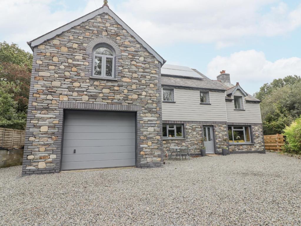 a stone house with a garage in the driveway at Hafan Dawel in Llanfyrnach