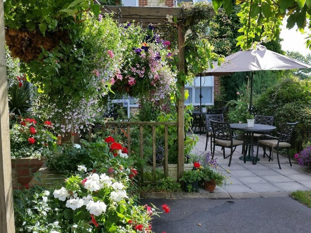 een tuin met bloemen en een tafel en een parasol bij Bolingbroke Arms & Hotel in Swindon