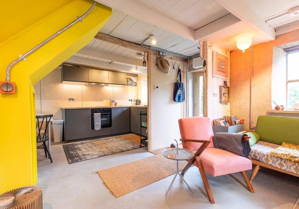 a living room with a couch and a kitchen at Ty Newydd - a scandi inspired cottage in Moylgrove