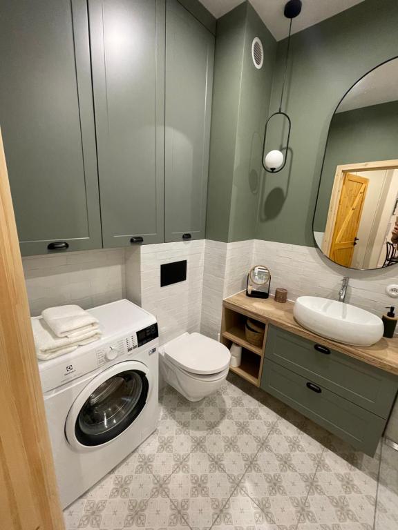 a bathroom with a washing machine and a sink at Apartament FOREST - HOME APART in Ostróda