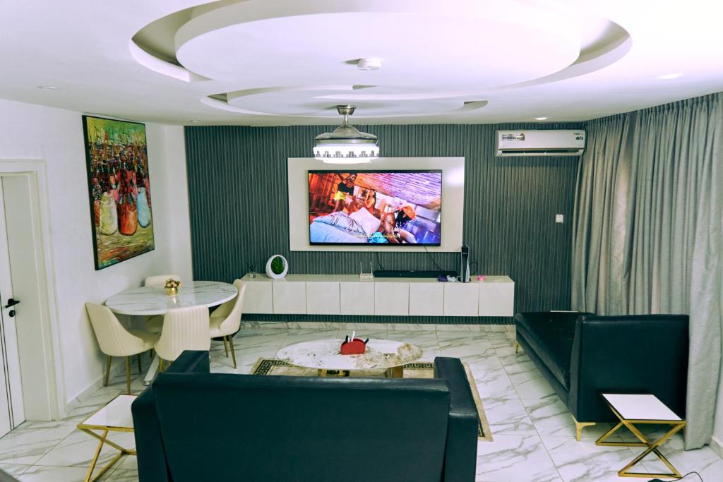 aPogee Home في أبوجا: غرفة معيشة مع تلفزيون وطاولة وكراسي