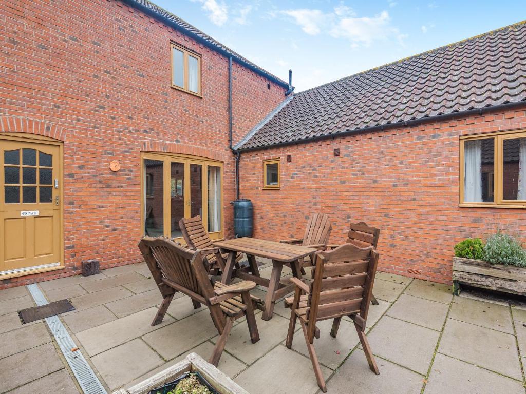 a patio with a wooden table and chairs at Walnut Cottage - Uk45579 in Maltby le Marsh