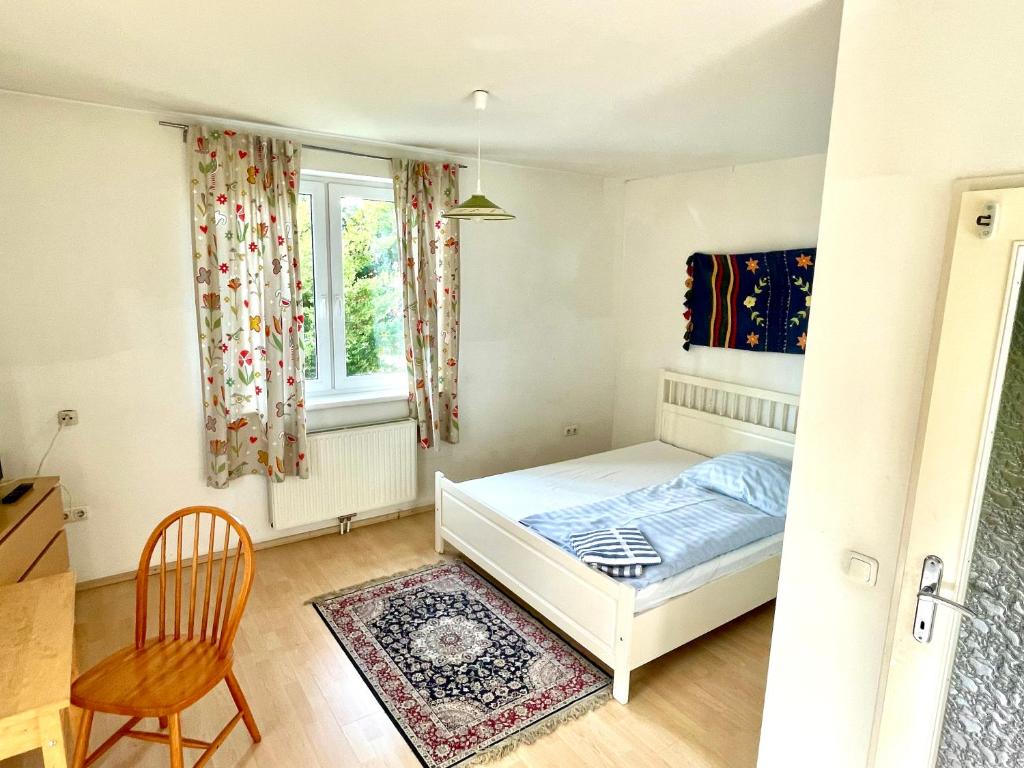 ein Schlafzimmer mit einem Bett, einem Stuhl und einem Fenster in der Unterkunft Gästezimmer Rothneusiedl in Wien