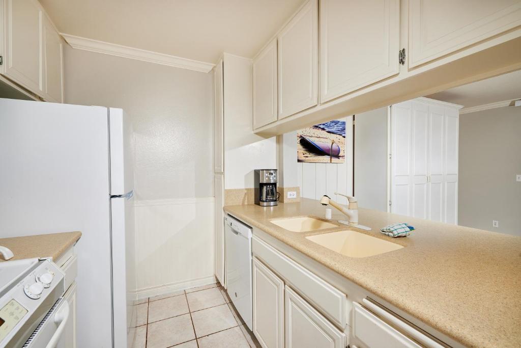 a white kitchen with a sink and a refrigerator at Seaside Cottage in Oceanside