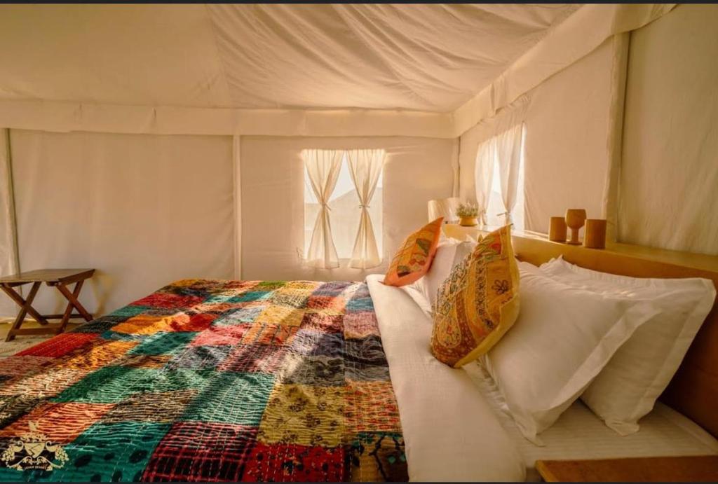 a bedroom with a bed with a colorful quilt at Magic Heritage Camp & Resort in Jaisalmer