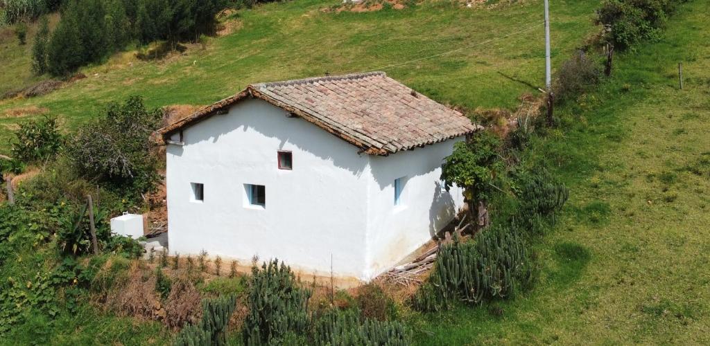 Ein weißes Haus auf einem Hügel auf einem Feld in der Unterkunft Casa Aurora Tibasosa Boyaca in Tibasosa