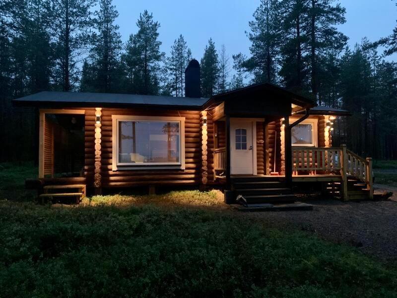 a log cabin with a porch and lights on it at Kaupinmaja, Ylläs - Hirsimökki järvi- ja tunturimaisemilla in Äkäslompolo